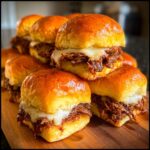 A tempting stack of Italian beef slider sandwiches featuring shredded beef and melted white cheese on brioche buns.