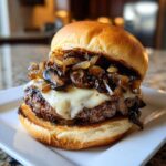 Close-up of a juicy Mushroom Swiss burger featuring melted Swiss cheese and a generous topping of sautéed mushrooms and onions.