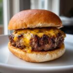 Close-up of a juicy Wagyu beef burger patty topped with melted cheddar cheese on a toasted brioche bun.