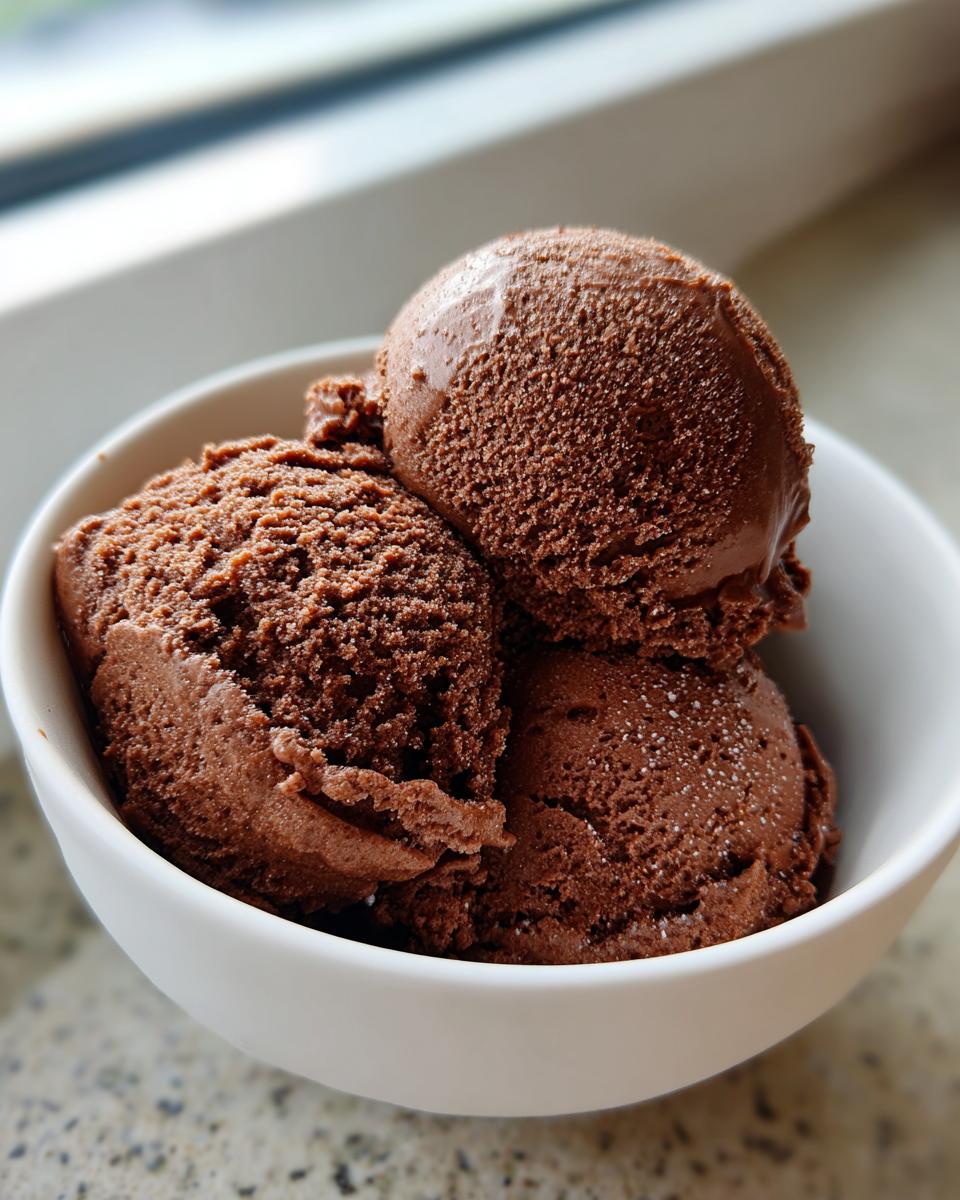 Three scoops of rich, dark Mexican chocolate ice cream served in a white bowl.