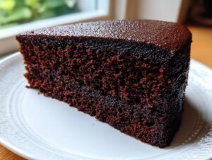 Close-up of a thick slice of dark, rich Moist devil's food cake showing its dense, moist crumb texture.