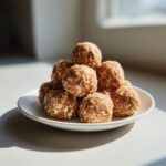 A small white plate stacked high with homemade peanut butter protein balls covered in visible oats.
