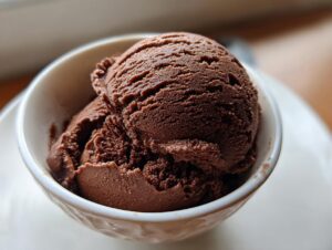 Close-up of two scoops of rich, dark brown chocolate gelato served in a small white bowl.