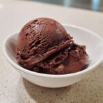 A perfectly scooped portion of rich, dark No churn chocolate ice cream served in a small white bowl.