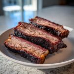 Three thick slices of juicy smoked beef brisket showing a deep red smoke ring and dark bark.