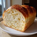 A close-up view of a freshly baked Sourdough brioche loaf, showing its soft, airy interior crumb and rich, golden-brown top crust.