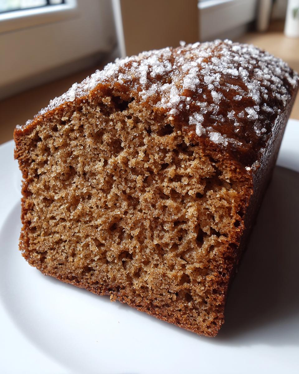 Close-up of a moist slice of Spiced applesauce cake showing its crumb texture and coarse sugar topping.