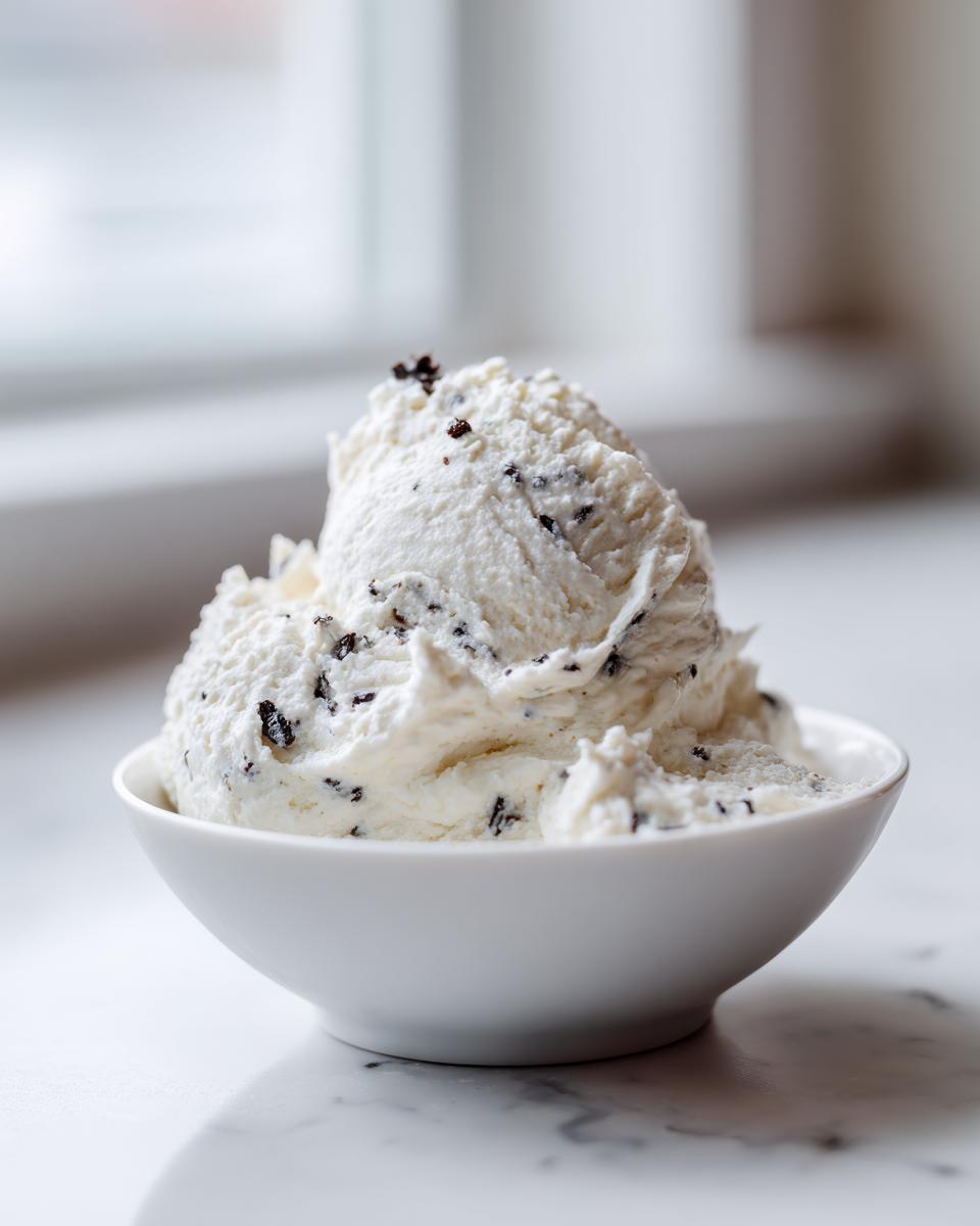 A generous scoop of creamy vanilla bean rice pudding speckled with dark vanilla seeds served in a small white bowl.