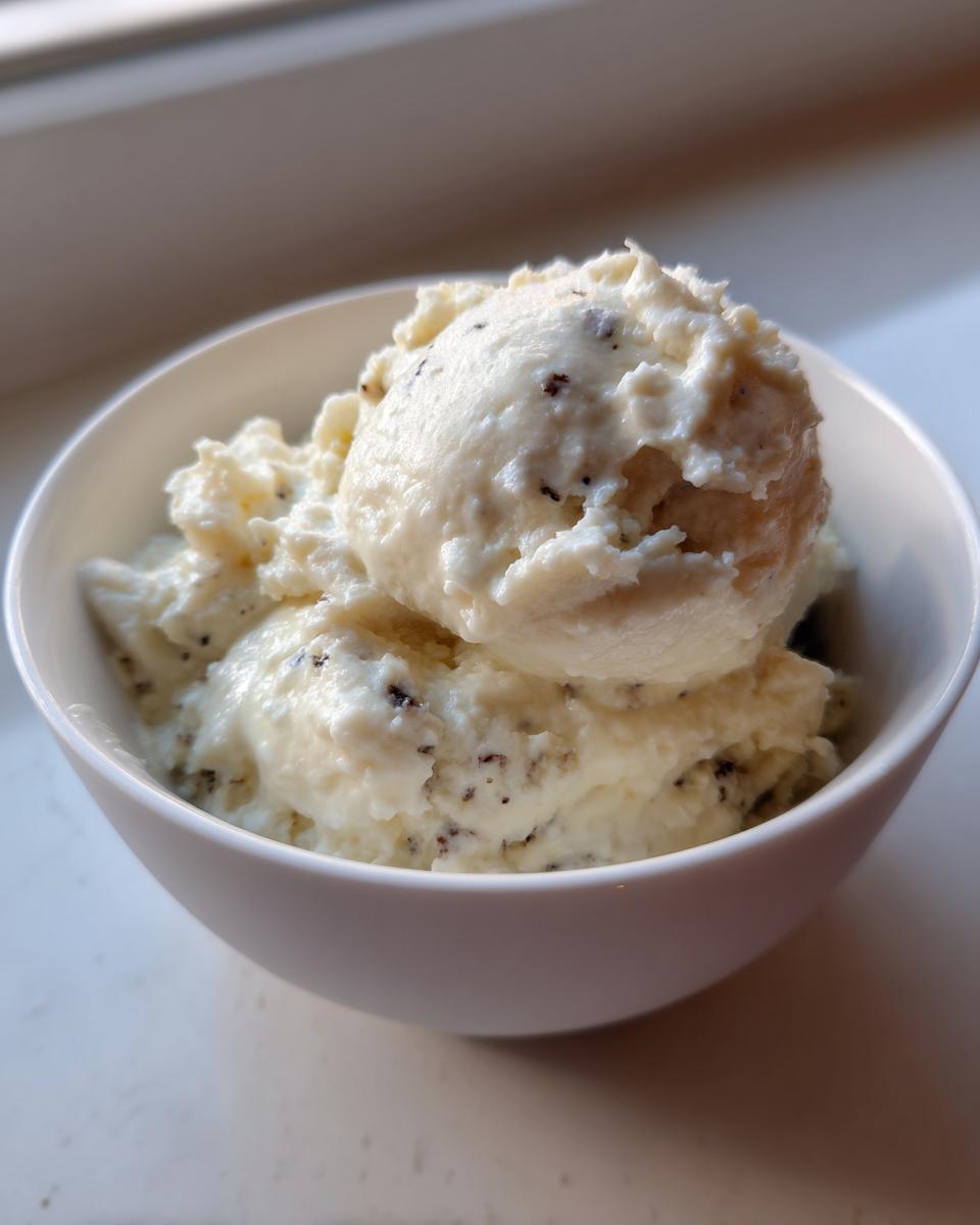 Two scoops of creamy Vanilla bean rice pudding speckled with dark vanilla bean seeds, served in a white bowl.