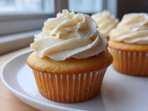 Close-up of a moist vanilla cupcake topped with a generous swirl of creamy vanilla buttercream frosting.