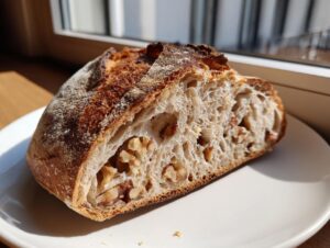 A close-up of a freshly baked Walnut Sourdough Bread slice showing an open, airy crumb texture studded with large walnut pieces.